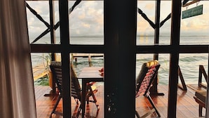 A wooden deck with two chairs and a table, overlooking a body of water. - Casa Acuario (Bocas del Toro)