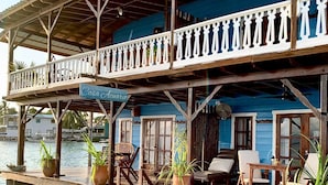 A two-story wooden structure with a balcony, overwater seating area, and clear water. - Casa Acuario (Bocas del Toro)