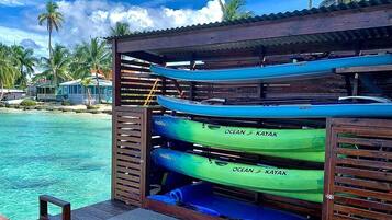 A wooden structure with kayaks labeled "Ocean Kayak" and "Malibu 95" stored inside.