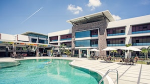 A modern hotel with a swimming pool, outdoor seating, and a large building with multiple windows. - Laguna Hotel (Port Moresby)