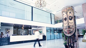 A hotel lobby with a reception desk, a large decorative sculpture, and a chandelier. - Laguna Hotel (Port Moresby)