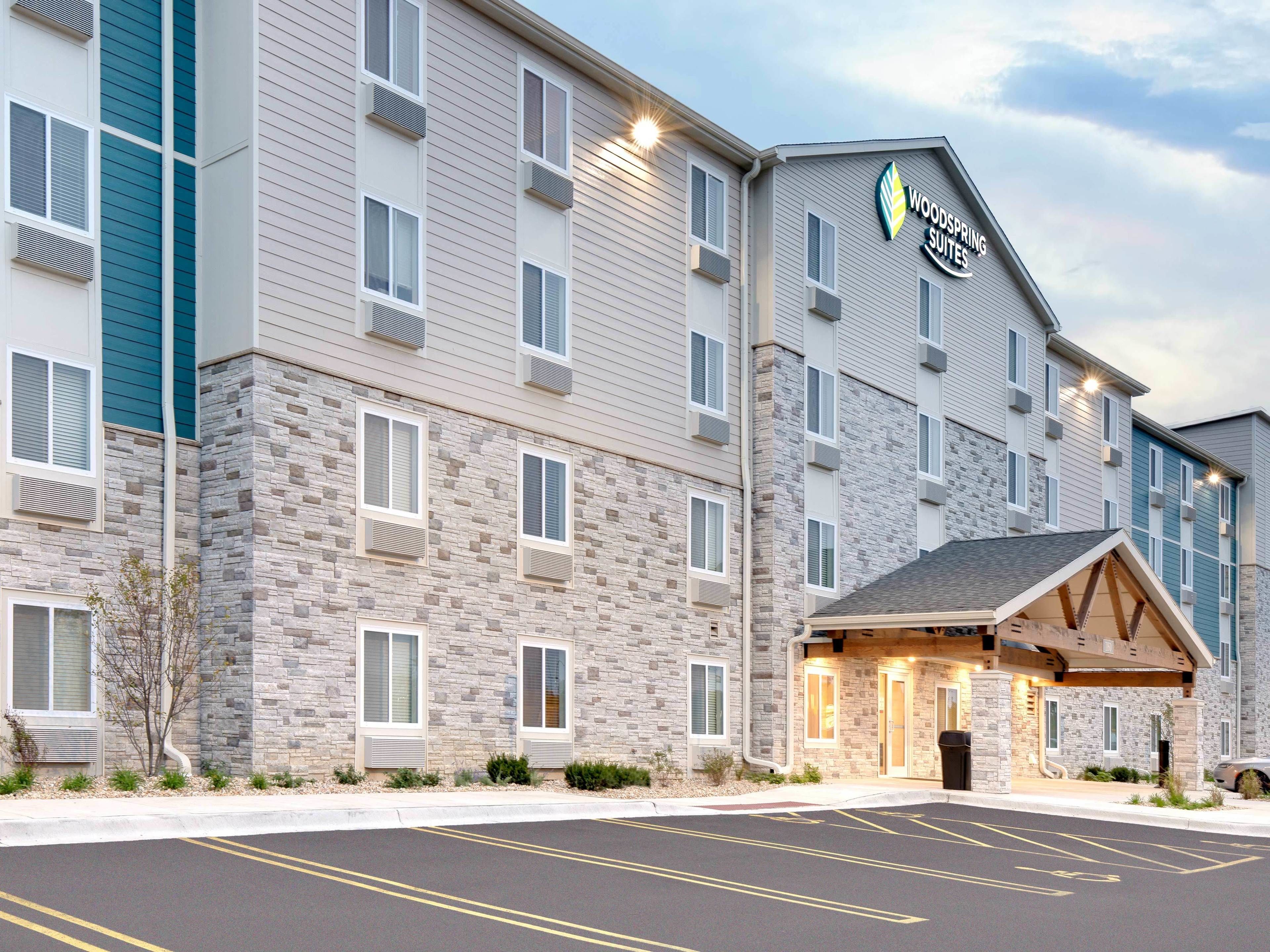 A multi-story hotel with a stone facade and a sign reading "Woodspring Suites."