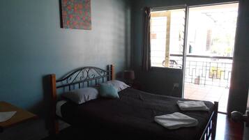 A bedroom with a bed, a window, and a door.