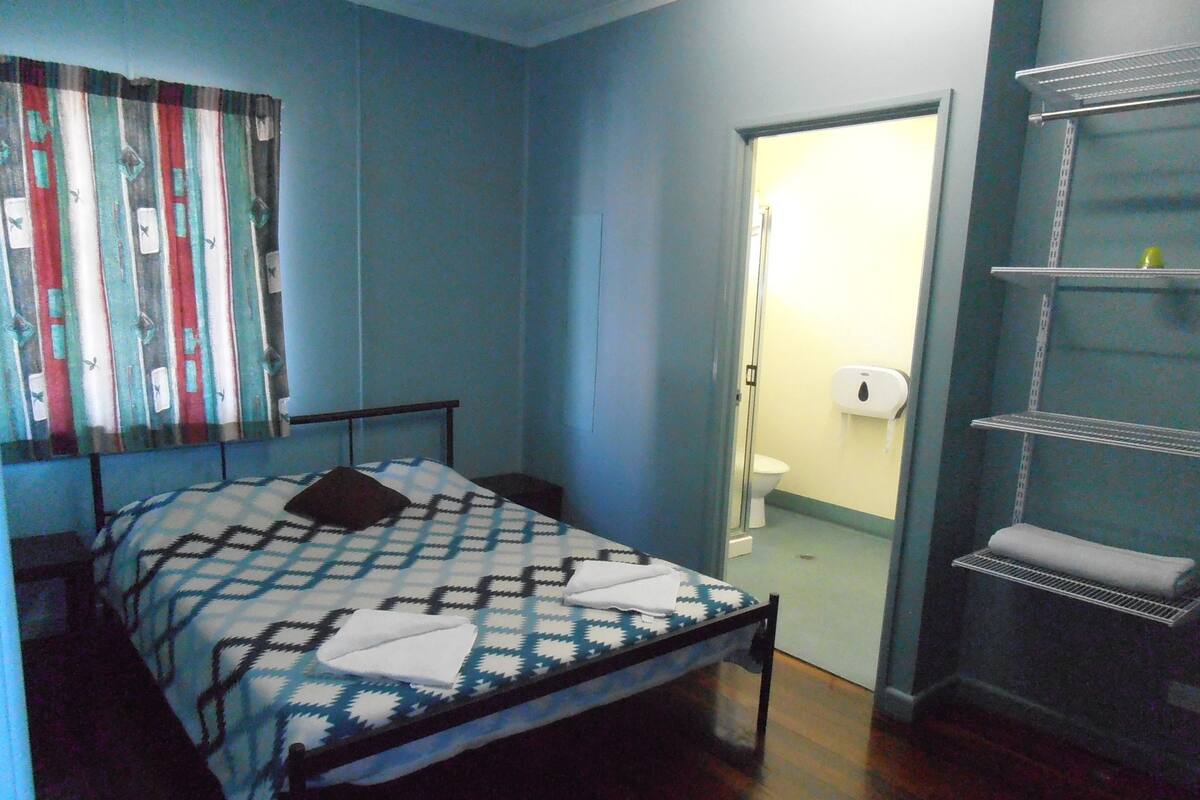 Ein Schlafzimmer mit einem Bett, einer Tür zu einem Badezimmer und einem Regal mit Handtüchern.