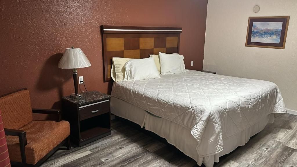 Une chambre d’hôtel avec un lit, une table de chevet, une lampe et une chaise.