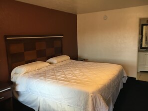 A hotel room with a bed, a nightstand, and a dresser.