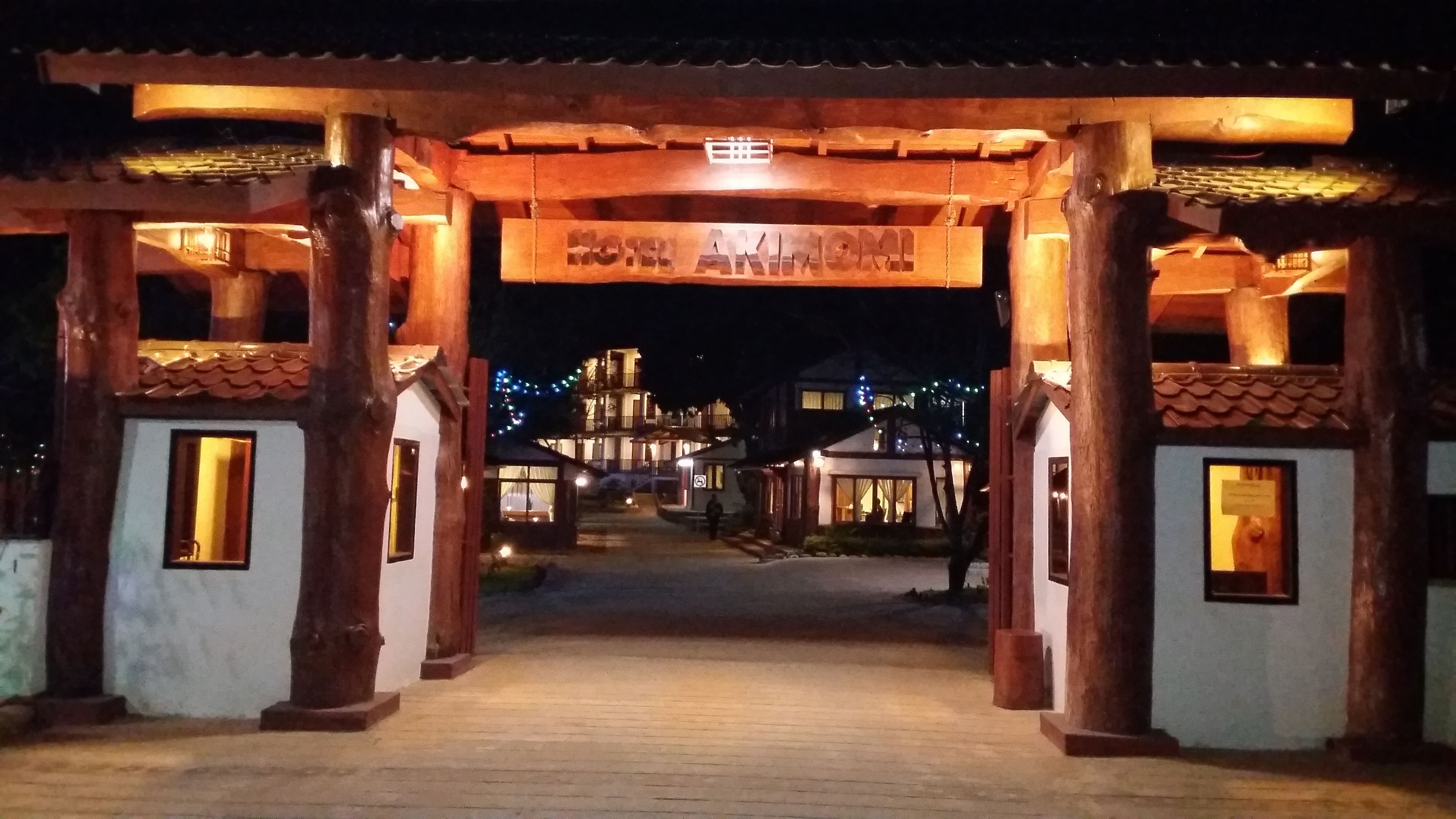 Un arco de madera tradicional que da acceso a un edificio con varias ventanas y un letrero en la parte superior.