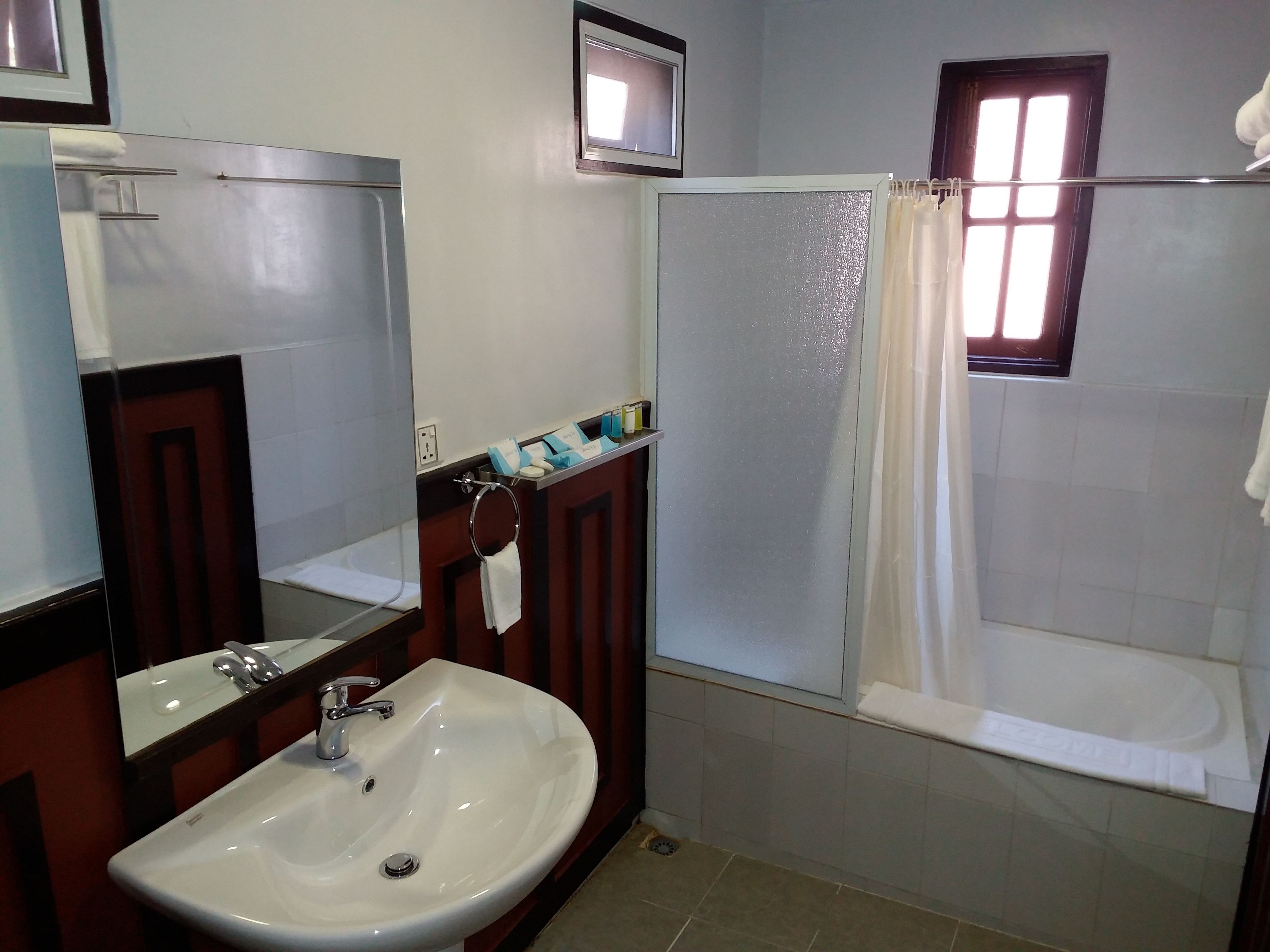 A bathroom with a sink, mirror, towel rack, and a shower area.