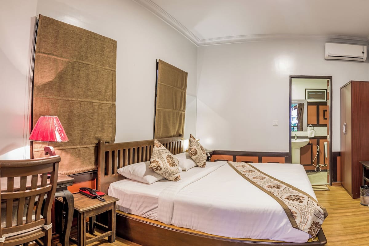 Una habitación de hotel con cama, escritorio con lámpara, silla, mesita y armario.