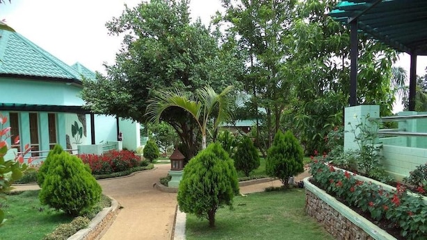 A garden pathway leading to a building with a green roof, surrounded by well-maintained hedges and flowering plants. - Hsaung Thazin Hotel Pyin Oo Lwin (Pyin Oo Lwin)