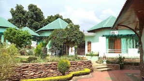A courtyard with multiple buildings, stone walls, and a variety of plants. - Hsaung Thazin Hotel Pyin Oo Lwin (Pyin Oo Lwin)