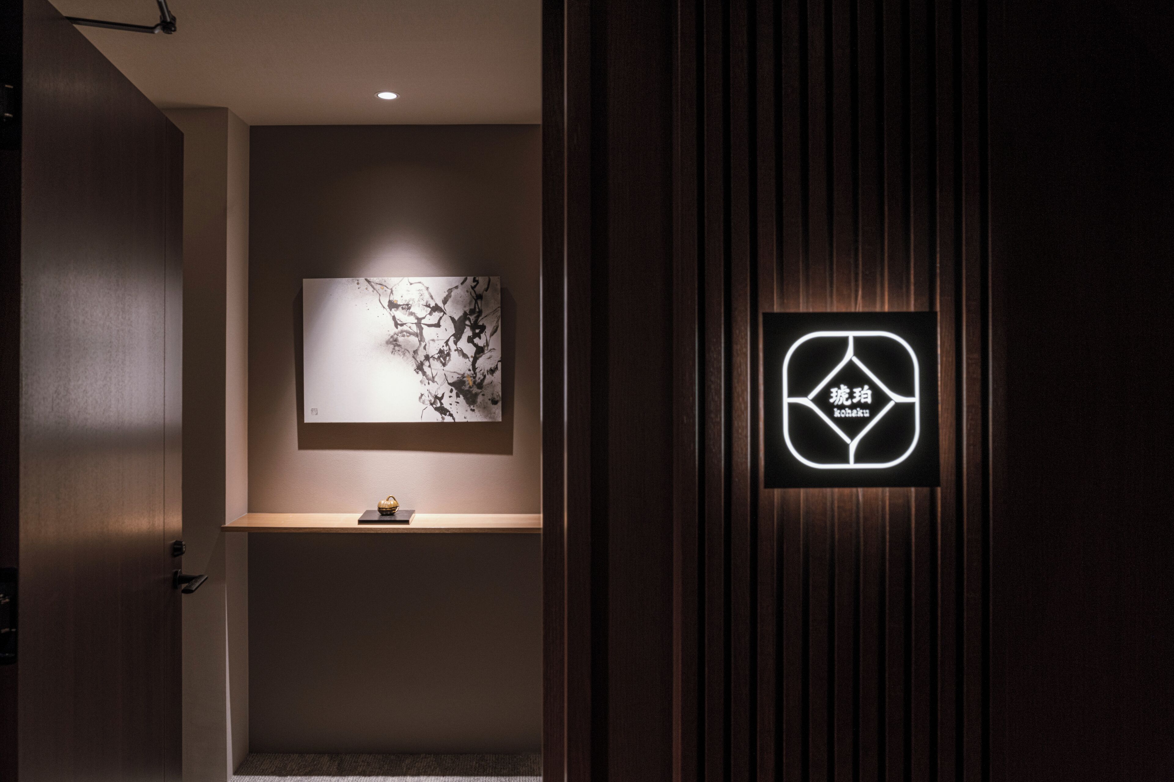 Un área de recepción con diseño moderno, que presenta un panel de pared de madera, una obra de arte abstracta enmarcada y un letrero de neón con caracteres chinos.