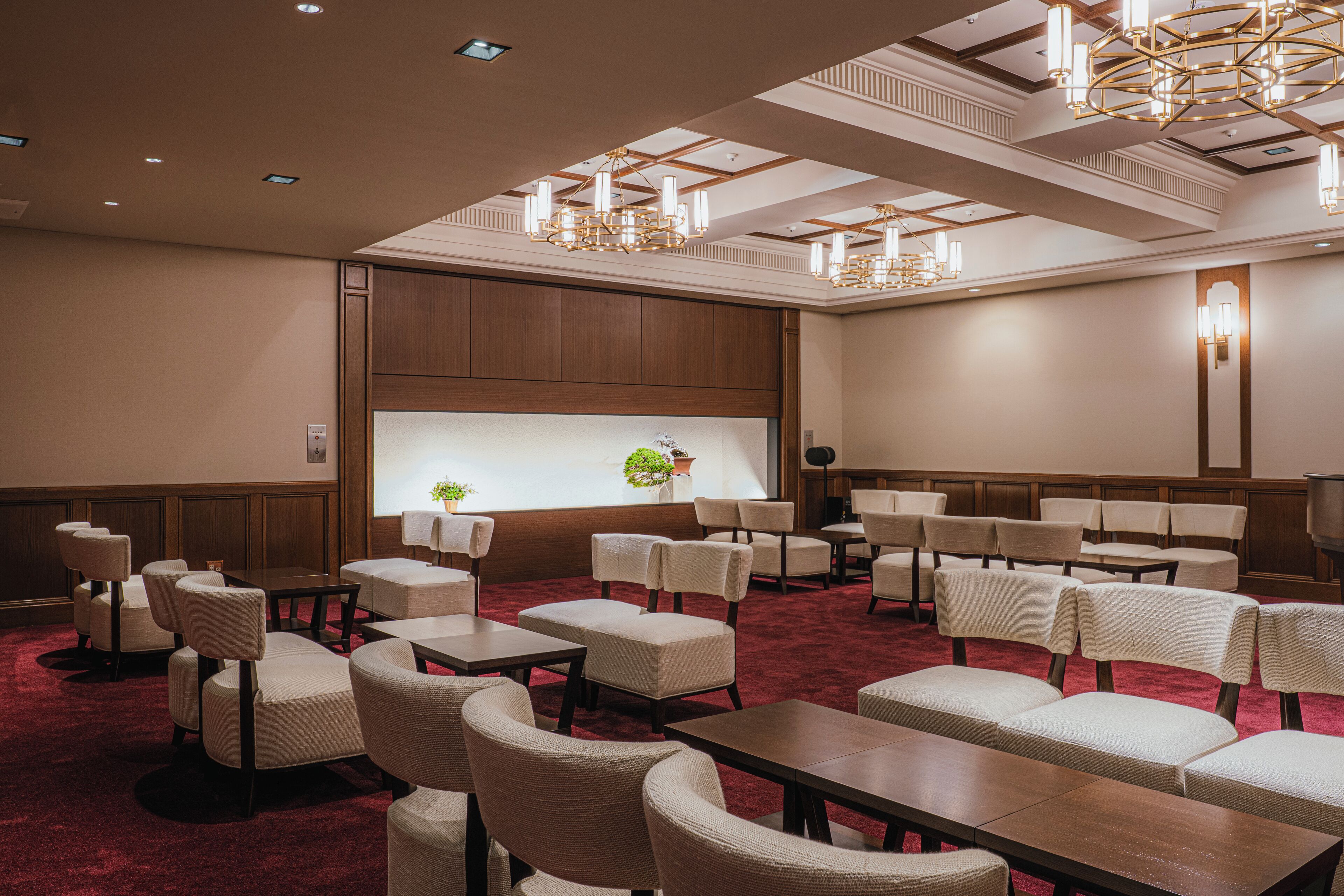 A conference room with multiple tables and chairs, a large screen, and a chandelier.