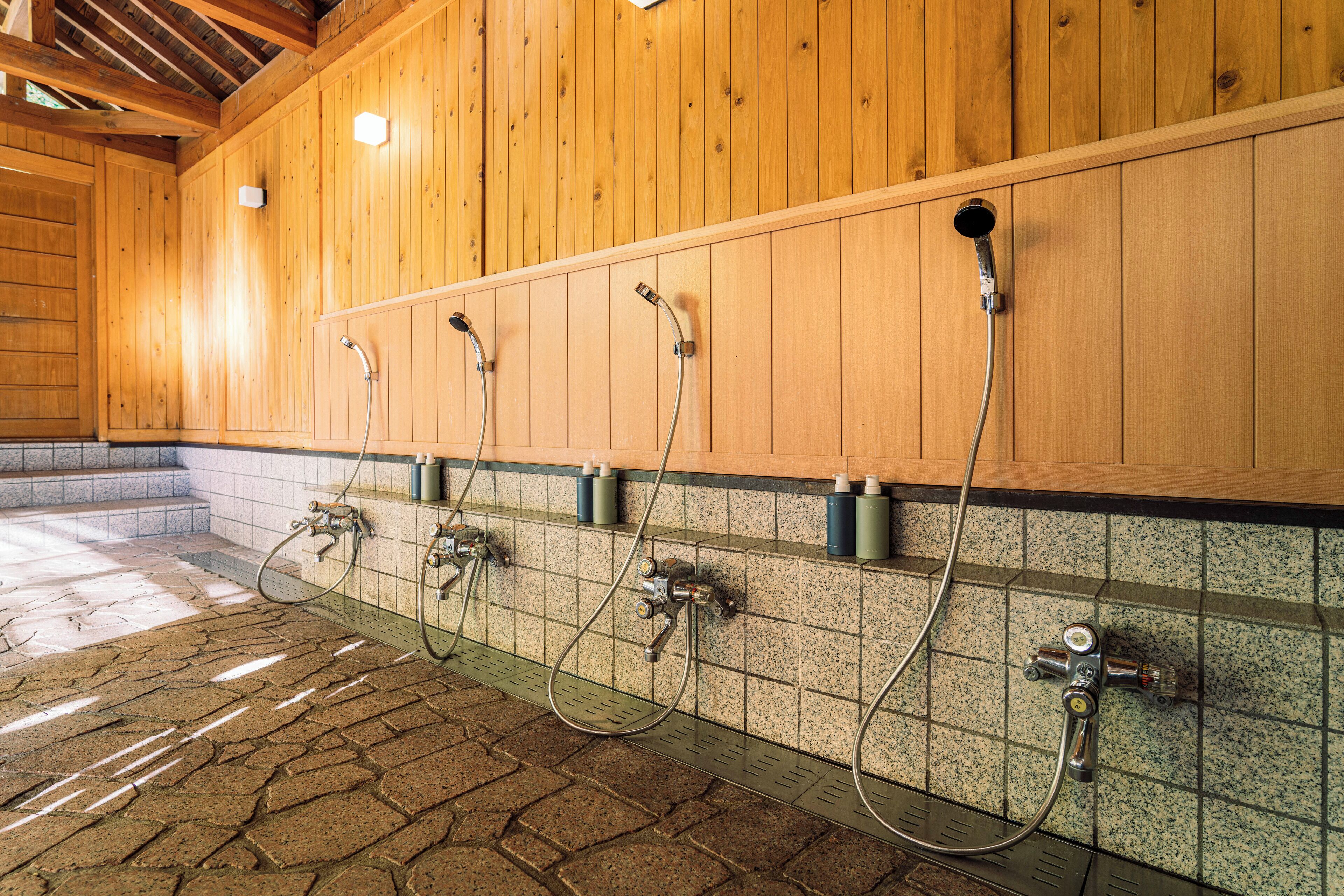 A public shower area with multiple showerheads and faucets on a tiled wall.