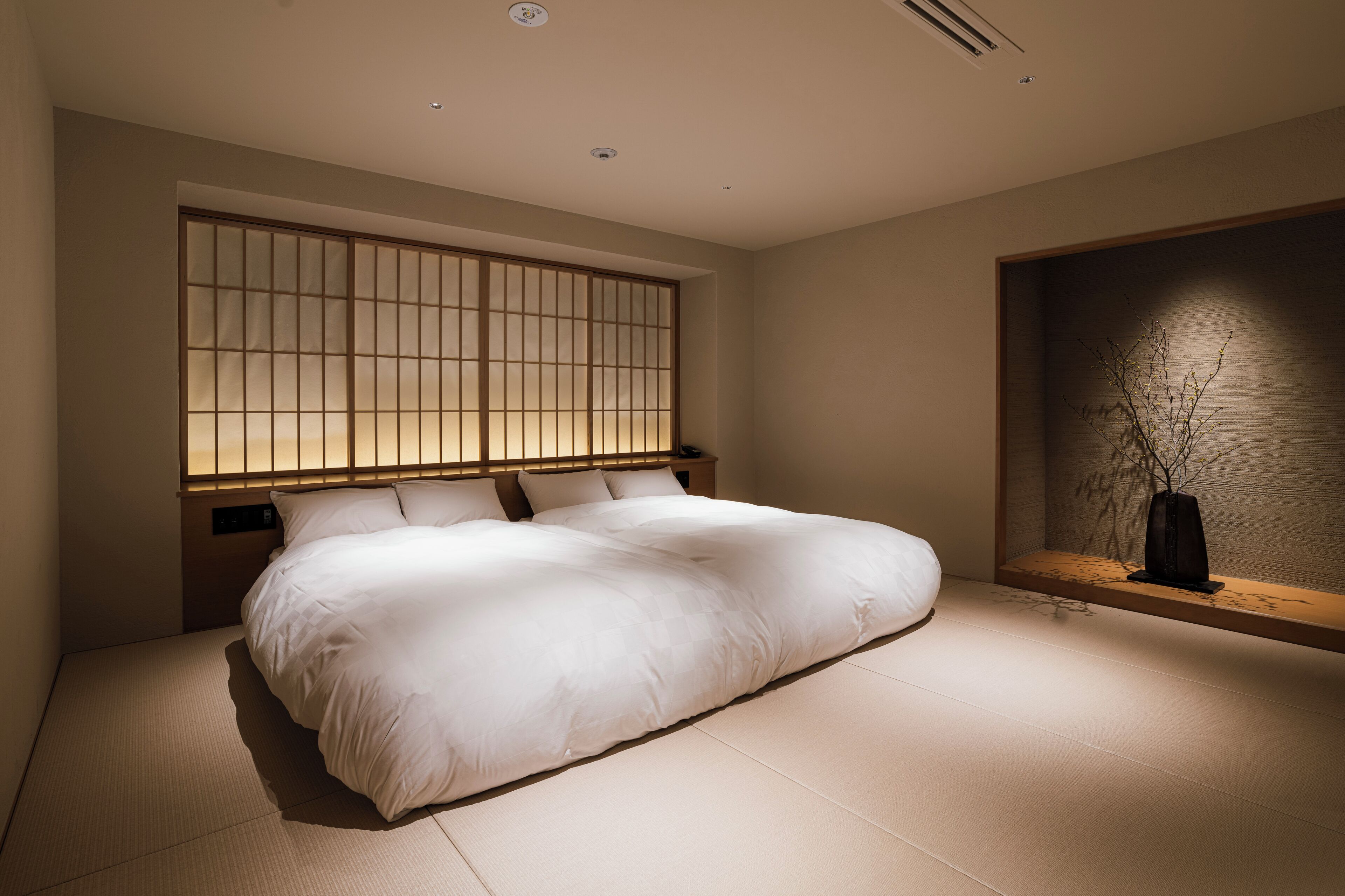 A modern bedroom with a large bed, a sliding shoji screen, and a minimalist decor.