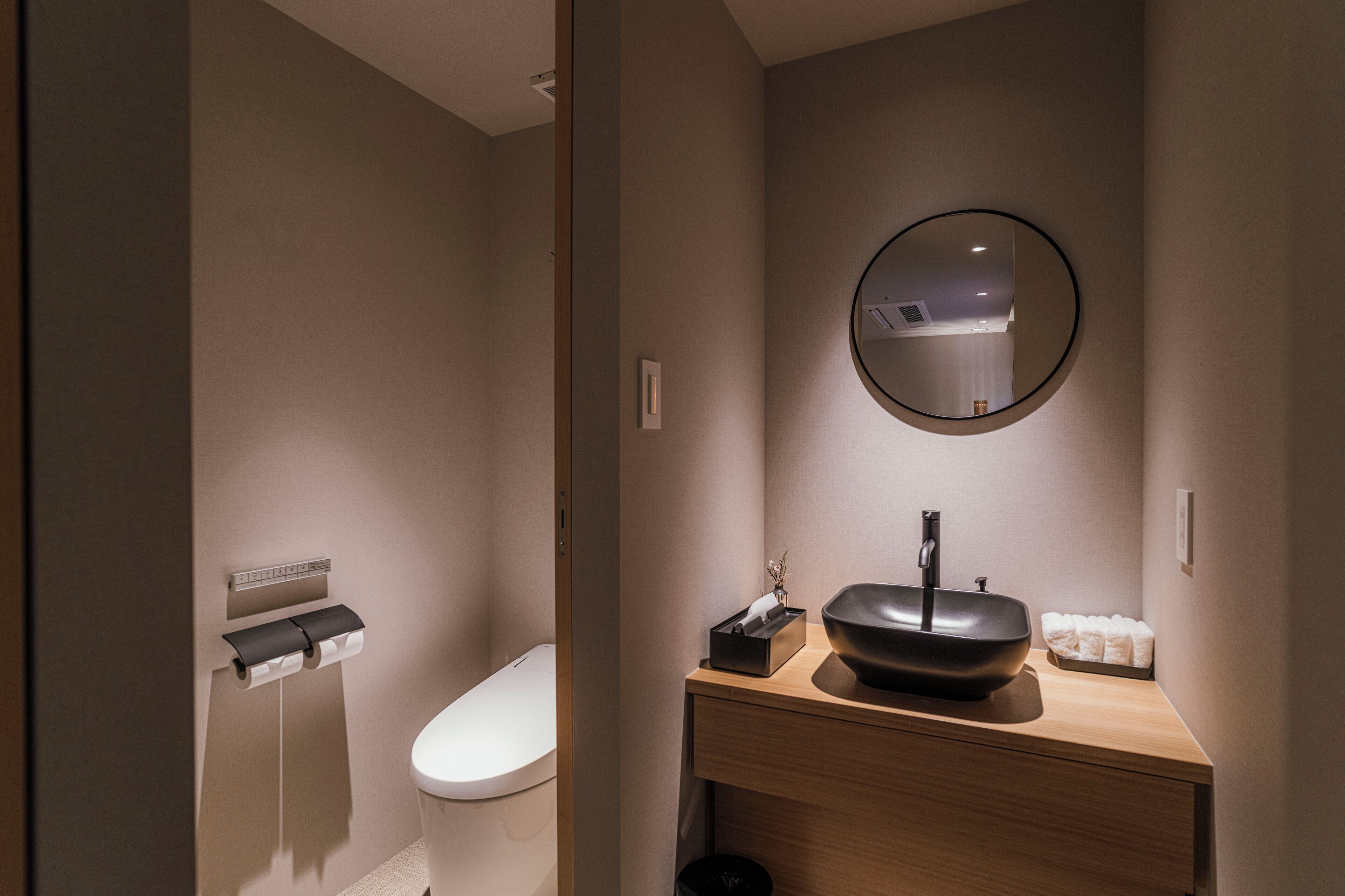 Une salle de bain moderne équipée de toilettes, d’un lavabo avec miroir et d’un porte-serviettes.