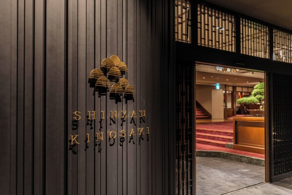 A hotel entrance with a dark facade and a sign reading "SHINZAN KINGOSAKI".