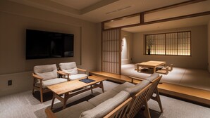 A modern living room with a flat-screen TV, a sofa, a coffee table, and a traditional sliding door. - Shinzan (Toyooka)