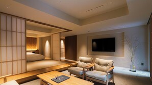 A modern living room with a sofa, two armchairs, a coffee table, and a TV mounted on the wall. - Shinzan (Toyooka)