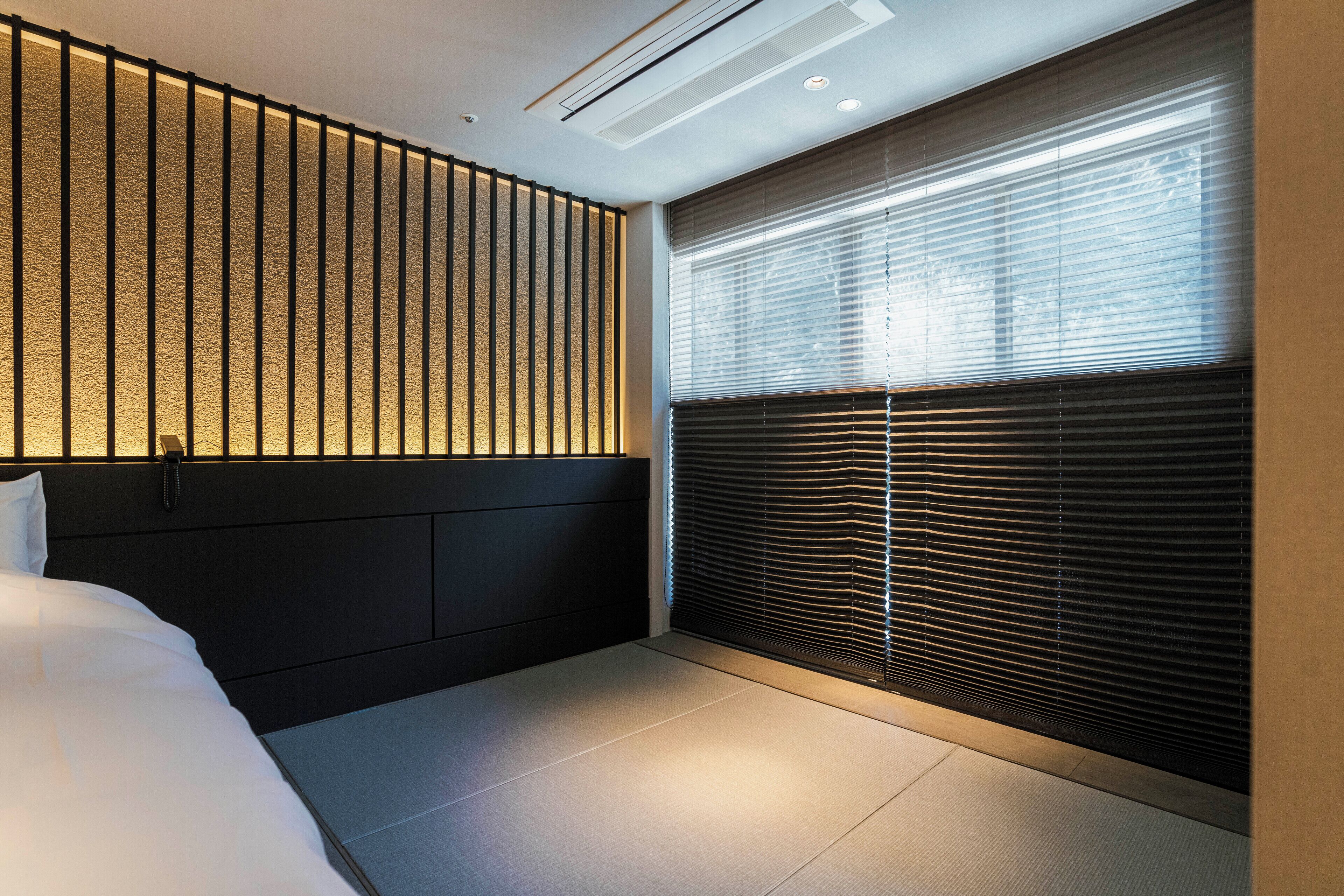 A modern bedroom with a bed, a wall with vertical slats, and a window with blinds.