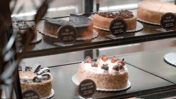 A bakery display case with various cakes and pastries, including a cherry cheesecake and an apple jalousie.