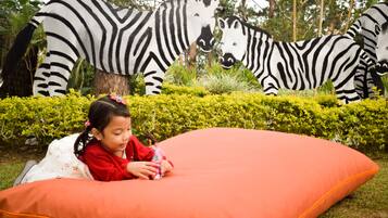 A child lying on an orange cushion with a zebra sculpture in the background.
