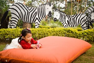 A child lying on an orange cushion with a zebra sculpture in the background.