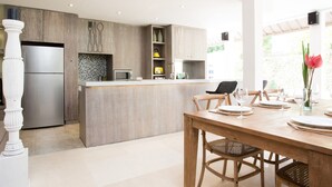 A modern kitchen with a built-in island, stainless steel appliances, and wooden cabinetry. - Allure Villas (Seminyak)