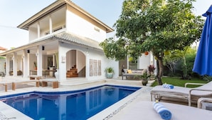 A modern house with a swimming pool, outdoor seating, and a garden. - Allure Villas (Seminyak)