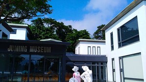 The exterior of the Juming Museum with modern architecture and glass doors.