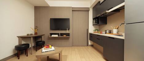 Una cocina moderna con un televisor de pantalla plana, armarios oscuros y una mesa de comedor de madera con fruteros.