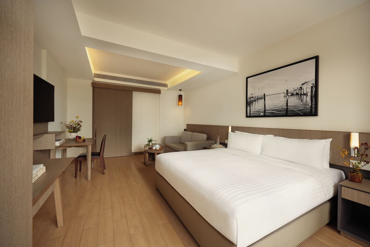 Una habitació d'hotel moderna amb un llit gran, una taula de treball amb cadira, una televisió i un quadre a la paret.