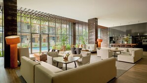 Una sala de estar moderna con vista a la piscina, amplias ventanas y una zona de cocina.