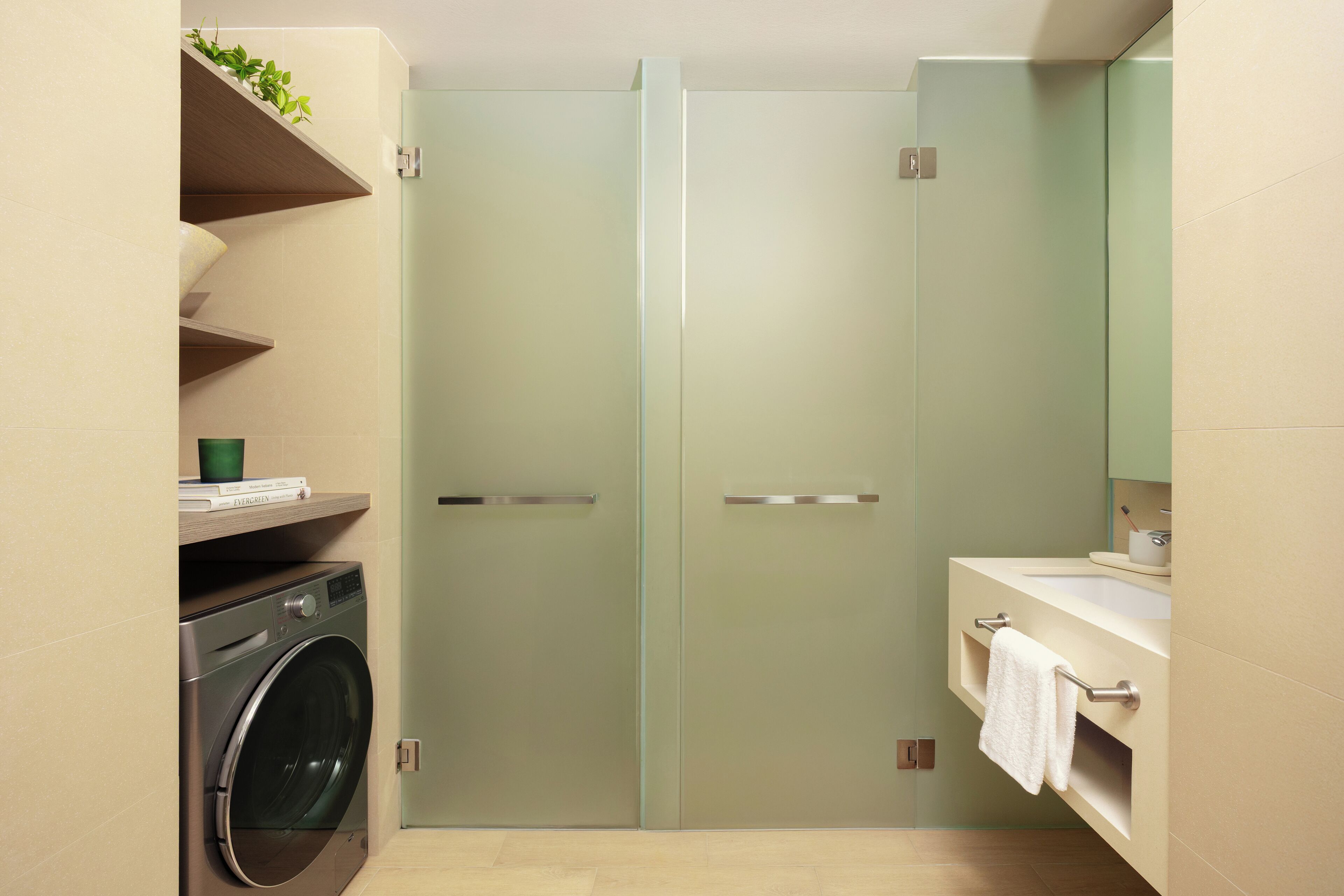 A modern bathroom with a washing machine, a glass shower enclosure, and a vanity with a mirror.