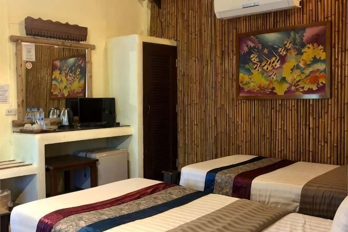 Ein Hotelzimmer mit zwei Betten, einem Schreibtisch mit Computer, einem kleinen Kühlschrank und einem großen Gemälde an der Wand.