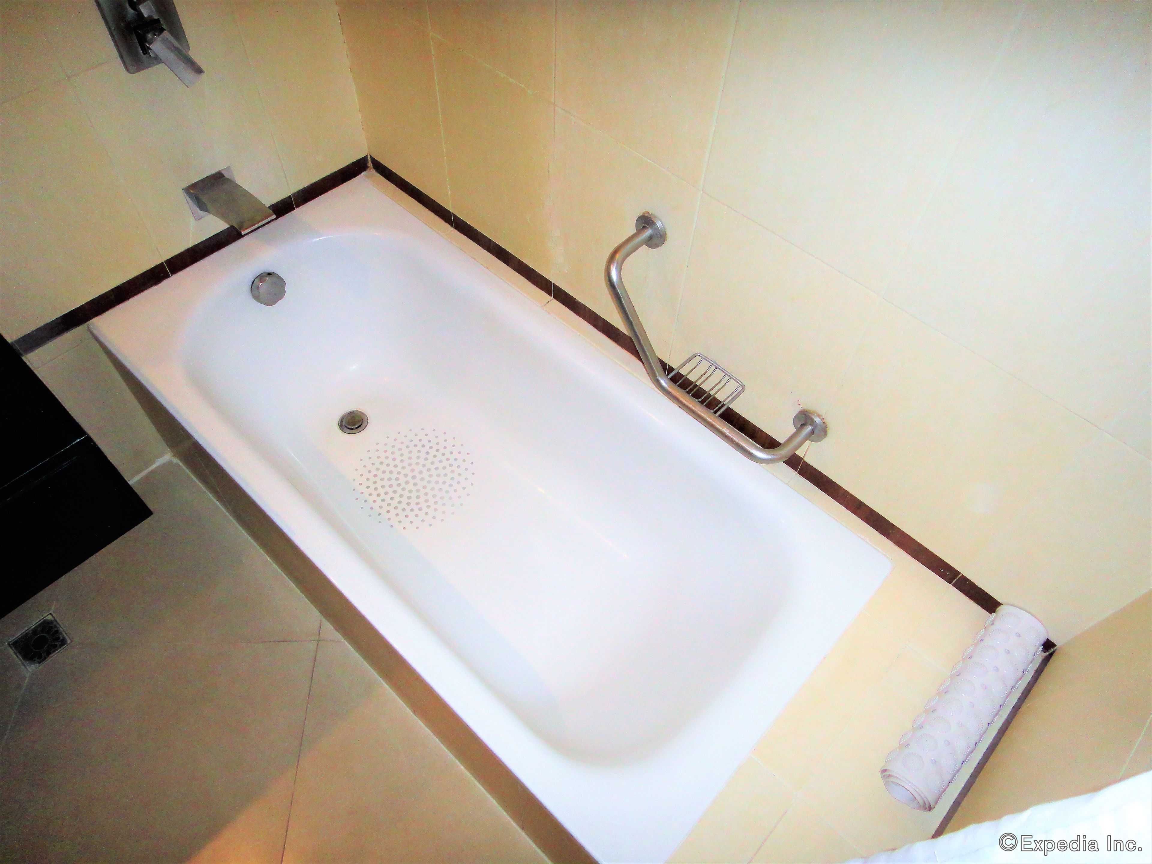 A standard bathtub with a handheld showerhead and a towel rack.
