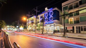 Un edificio de varios pisos con señalización iluminada, incluyendo un letrero 'Bear Packer' y un letrero 'Balkhotel Patong'.