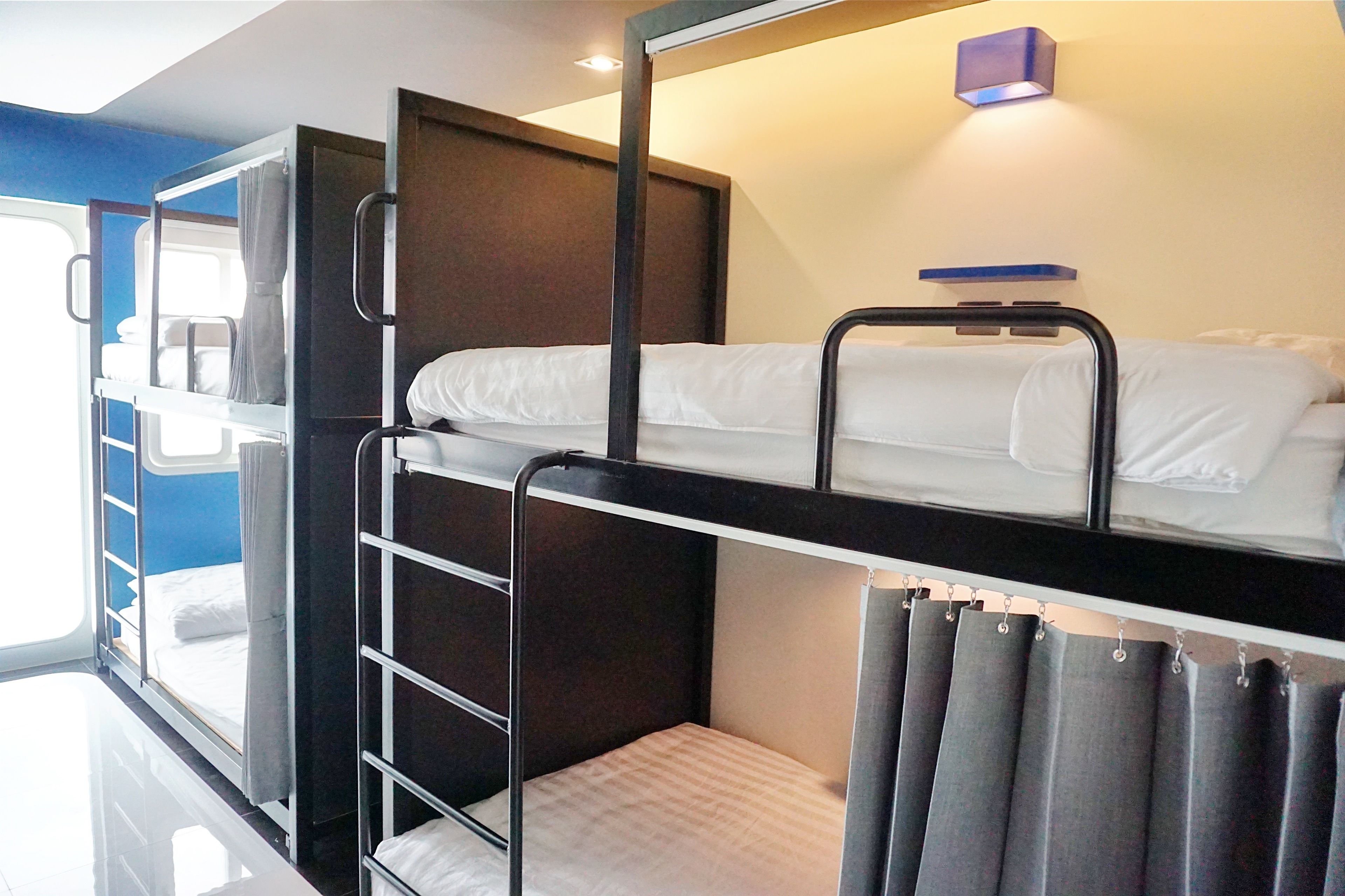 Une chambre avec un lit superposé, une échelle, une petite table et un rideau.