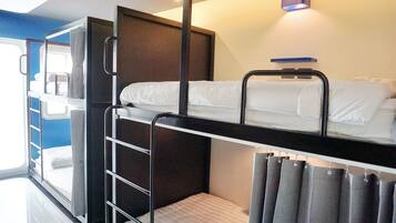 Une chambre avec un lit superposé, une échelle, une petite table et un rideau.