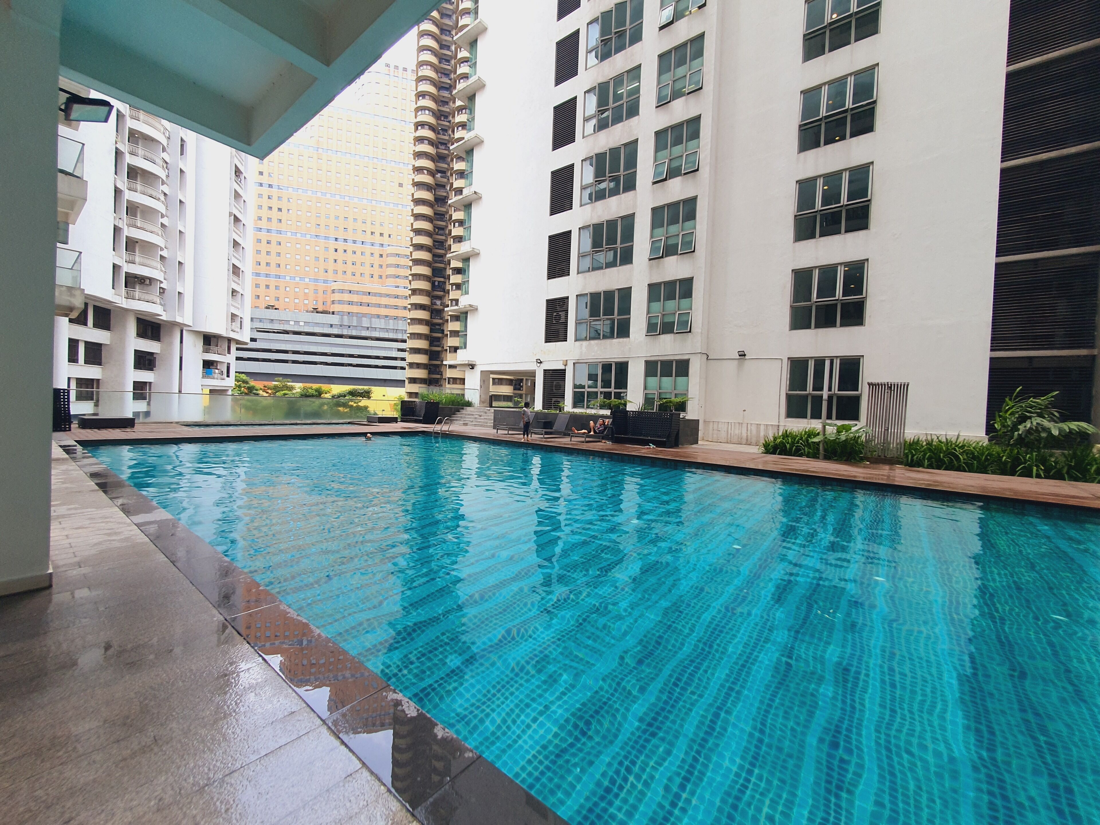 A swimming pool with tiled edges, surrounded by modern buildings with balconies and large windows.