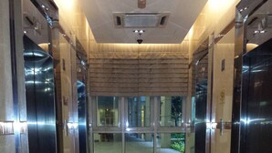 A corridor with elevators and a glass door leading outside.