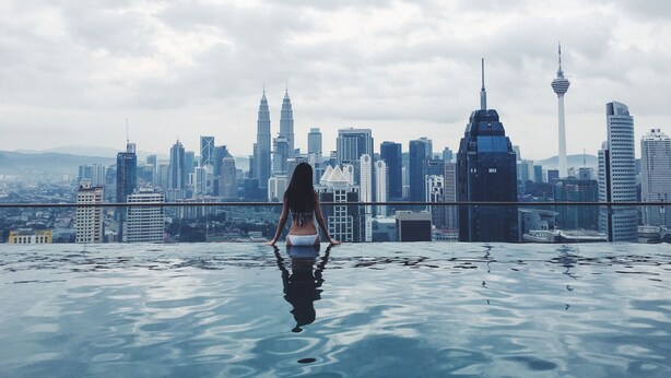 A person standing in a pool with a city skyline in the background.