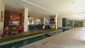 A spacious indoor area with a pool, seating areas, and a restaurant.