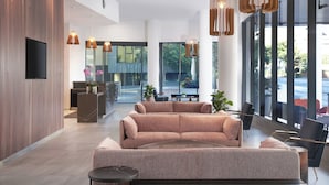 Un vestíbulo moderno con un sofá grande, un mostrador de recepción y ventanas amplias que dan a exteriores.