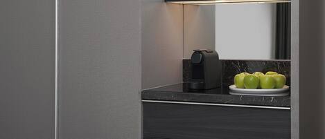 Una cocina moderna con encimera de mármol, una cafetera y un plato de manzanas verdes.