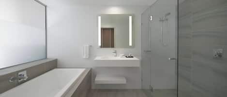 A modern bathroom with a glass shower enclosure, a large mirror, and a white sink.