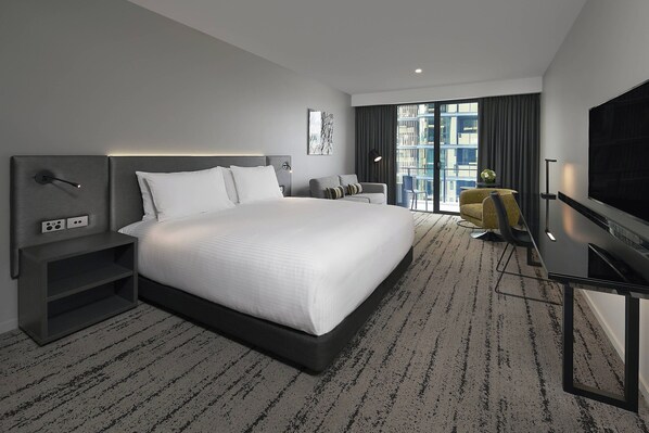 A modern hotel room with a large bed, a desk, a chair, and a TV. - Courtyard by Marriott Brisbane South Bank (South Brisbane)