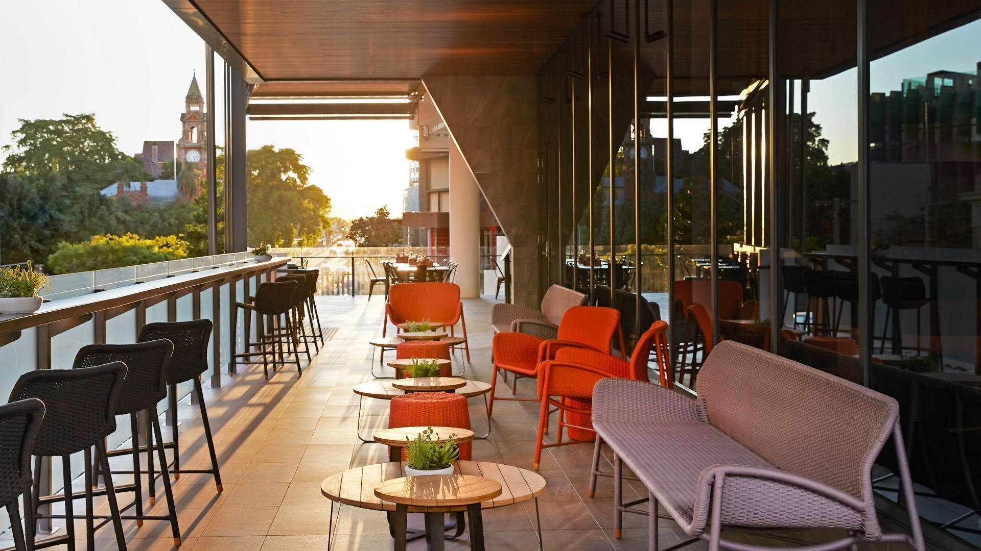 An outdoor seating area with tables and chairs, a wicker sofa, and a view of the cityscape.