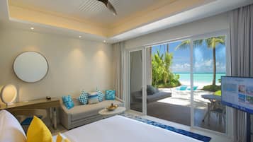 Una habitación de hotel con cama, escritorio, sofá y vista a la playa.