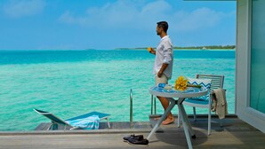 A man standing by a table with a view of turquoise waters. - Kandima Maldives (Kandima Island)